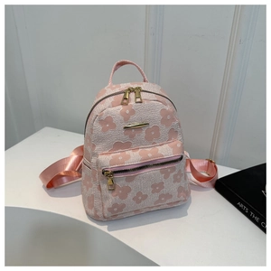 Gros plan d'un mini sac à dos rose avec texture florale et détails dorés brillants