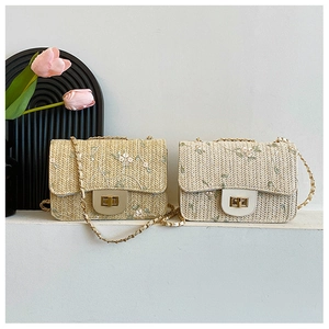 Detail of woven straw shoulder bag featuring floral embroidery and gold metal clasp