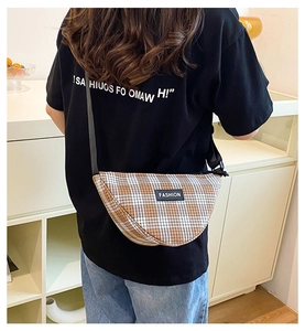Detail of checkered crescent crossbody bag with fashion label and black shoulder strap