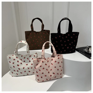 Close-up of corduroy tote bags with strawberry print in brown, black, beige and pink
