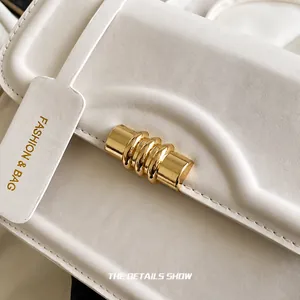 Macro detail of white lychee leather texture and golden cylindrical lock with a tag