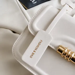 Detailed close-up of beige leather bag with gold buckle and fashion brand tag