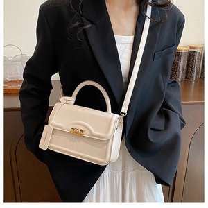 Chic cream leather handbag with gold twist lock shown on model in elegant business style