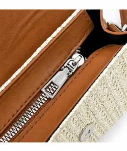 Détail de la fermeture éclair en métal argenté sur un sac bandoulière tissé crème et marron