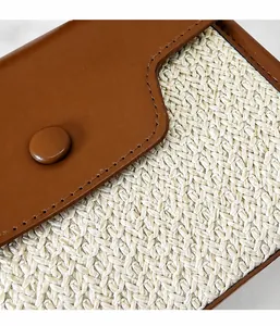 Détail du sac bandoulière en paille tressée avec rabat en cuir brun et bouton pression