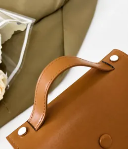 Détail de la poignée du sac en cuir marron avec des rivets métalliques argentés