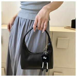 Dettaglio borsa hobo in pelle nera con ciondolo a mostro di peluche e cerniera