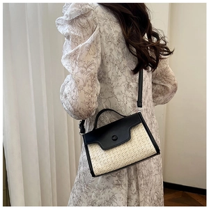 Vue latérale d'un sac bandoulière tissé beige avec rabat en cuir noir sur un mannequin