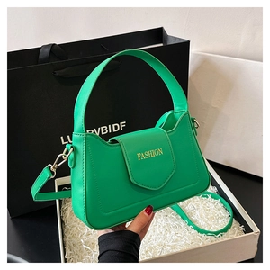 Détail d'un sac à main vert vif avec lettrage doré dans un coffret cadeau élégant