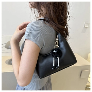 Dettaglio borsa hobo nera con un ciondolo a forma di mostro di peluche dalle gambe lunghe