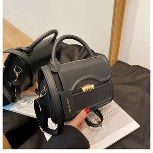 Detail of black matte leather handbag with gold twist lock and mirror reflection view