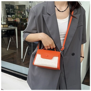Vue détaillée d'un sac bandoulière tissé orange et beige porté par un mannequin en costume