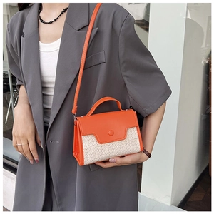 Détail du sac à main orange en cuir et texture tissée sur un blazer élégant