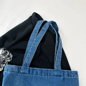 Détail de la bandoulière du sac cabas en jean bleu avec coutures marron contrastées