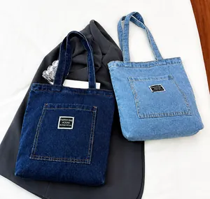 Détail de sacs cabas en denim bleu foncé et clair avec poches avant et étiquettes mode