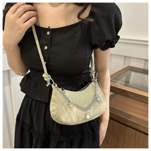 Detail of light green pleated crescent bag with pearl star charms and silver chain strap