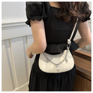Detail of white half-moon bag featuring cloud-embossed texture and silver heart chain