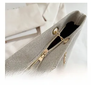 Detail eines glatten Goldreißverschlusses und Lederriemens an beiger Web-Tasche