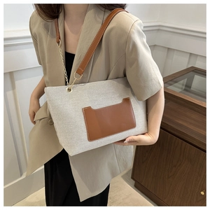Detail der grauen Nylon-Einkaufstasche mit brauner Ledertasche und goldener Kette