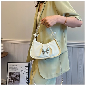 Détail du sac croissant plissé blanc cassé avec papillon en métal et anse en perles