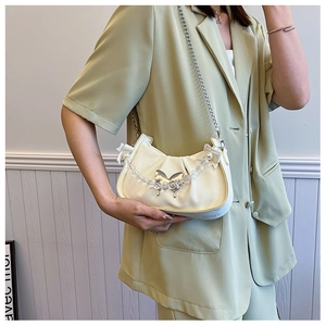 Détail du sac plissé crème avec papillon argenté et bandoulière en perles élégante