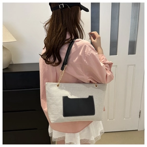 Schicke Canvas-Einkaufstasche mit schwarzer Ledertasche und goldener Kette am Modell