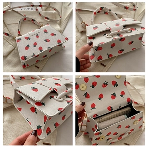 Detail van leren tas met aardbeienprint, ruime binnenkant en magnetische sluiting