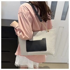 Detail der Canvas-Tragetasche mit schwarzer Ledertasche und goldener Ring-Hardware am Gurt