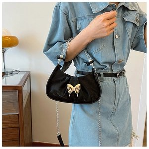 Détail du sac croissant plissé noir avec fermoir papillon doré et anse perlée