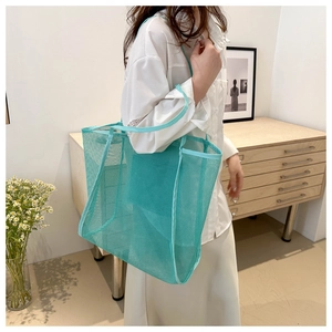 Detailweergave van een ruime turquoise mesh draagtas met canvas handvatten voor de zomer