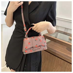 Model met kleine lila crossbodytas met aardbeienprint en elegante leertextuur voor