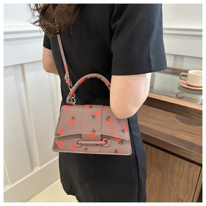 Modieuze crossbodytas met aardbeienprint en litchi-textuur in een informele levensstijlomgeving
