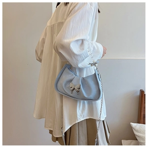 Détail du sac plissé bleu clair avec papillon argenté et bandoulière en perles