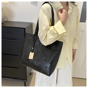 Close-up of black crocodile pattern tote bag with polished finish and rectangle tag