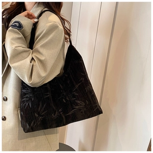 Detail of a black large tote bag featuring delicate leaf jacquard fabric on a shoulder strap