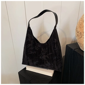 Detail of black velvet hobo bag with subtle leaf patterns on textured fabric surface