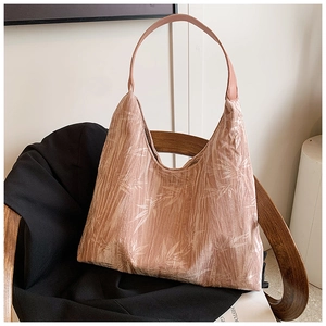 Detail of canvas tote bag with leaf pattern hanging on a wooden chair in soft light