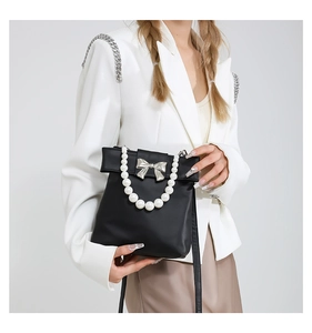 Détail du sac en similicuir noir avec poignée en perles et boucle de noeud argentée