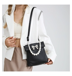 Détail du sac en cuir PU noir avec anse en perles blanches et boucle nœud argenté