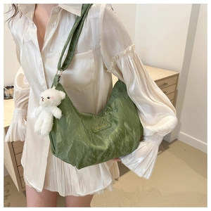 Detalle del bolso de hombro media luna verde en nailon con un lindo oso de peluche