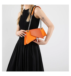 Detalle de bolso bandolera naranja brillante con textura de hoja y cadena de plata