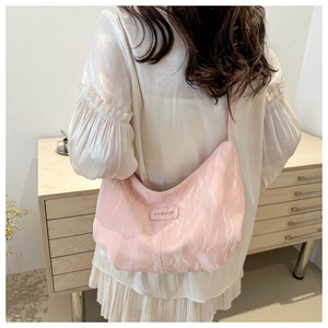 Detalle del bolso hobo rosa plisado mostrando textura suave y forma de media luna en el hombro
