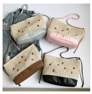 Close-up of four woven straw bucket bags with strawberry embroidery and leather bases