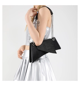 Bolso asimétrico negro con purpurina llevado por una modelo con un atuendo plateado