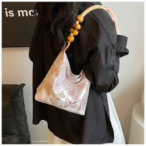 Détail de broderie papillon et poignée en perles de bois sur sac bandoulière rose