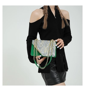 Close-up of green and patterned texture bag with gold chain strap on a model shoulder
