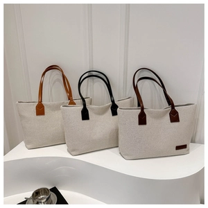 Detailed macro view of minimalist canvas tote bags with premium leather trim and stitching