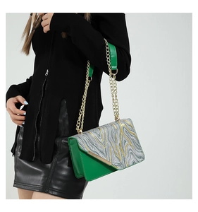 Detail of green shoulder bag with contrasting silver gold texture flap and gold chain