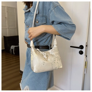 Close-up of vintage Chinese style cream shoulder bag with floral print and bead charm