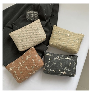 Detalle de bolsos bordados de paja en beige, verde azulado, marrón y gris oscuro